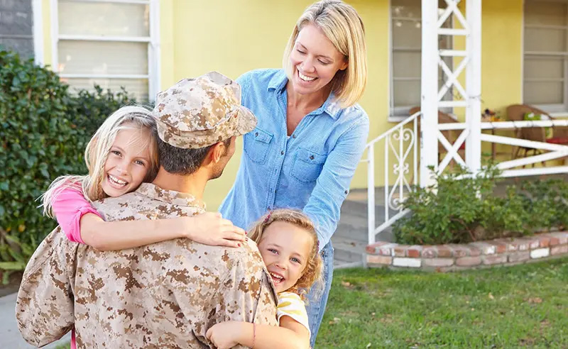 Family hugging their military father